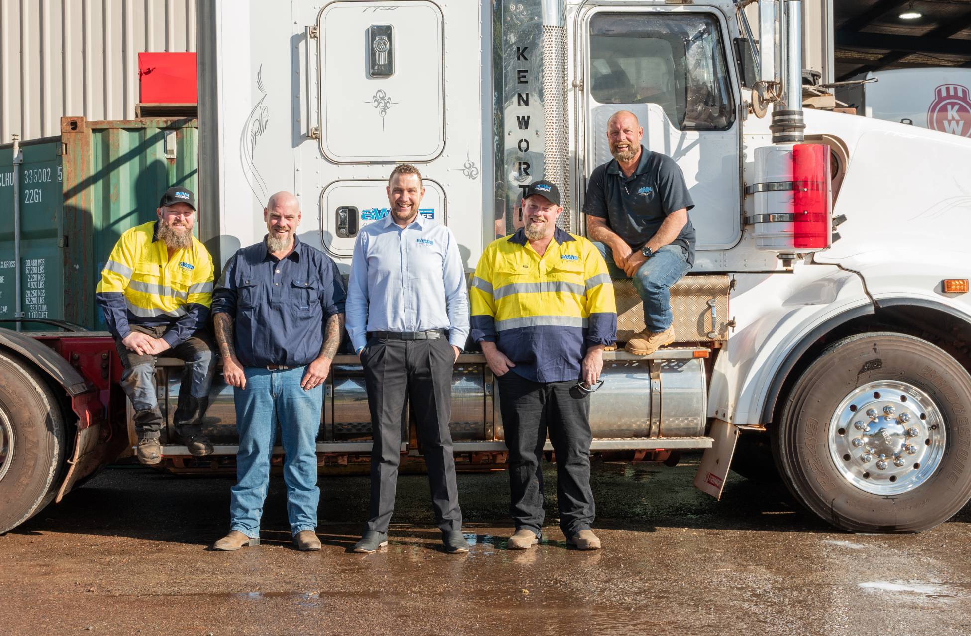 Australia Wide Haulage team standing in front of an AWH prime mover at the Hazelmere yard